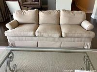 Front view of three-seat beige sofa on light rug