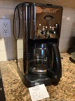 Front view of Cuisinart coffee maker showing control panel and glass carafe on granite countertop.