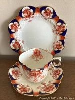 Front view of cup nestled in saucer with plate behind, showing floral pattern and shape