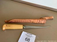 Full view of the J. Marttiini knife with wooden handle and the leather sheath beside it on a flat surface.