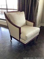 Front-right angled view of the lounge chair showing off-white linen upholstery and wooden frame with caster wheels