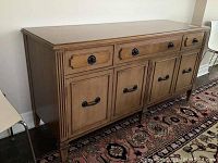 Three-quarter front view of oak sideboard credenza, showing all drawers and cabinet doors.