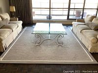 Living room setting showing full rectangular rug with glass-top coffee table and two sofas