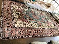 Full view of the rug under glass coffee table showing overall pattern and condition