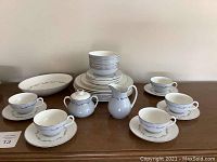 Full view of the dinnerware set showing stacked plates, cups with saucers, sugar bowl, creamer, and the large serving bowl