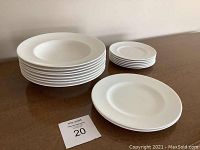Full lot showing stacks of 12 rimmed plates and 4 smaller rimmed soup bowls together on table.