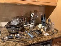 Overview of the kitchen counter showing the knife block, pots, colanders, and assortment of utensils including spoons, ladles, and tongs.