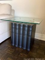 Side view of table showing glass top and faux books as base