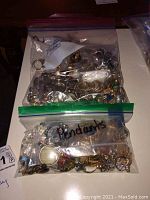 Two ziplock bags labeled 'Pins' and 'Pendants' containing numerous costume jewelry items.