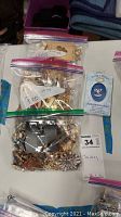 Three resealable plastic bags containing assorted costume jewelry pins or brooches in various styles and colors shown from above.