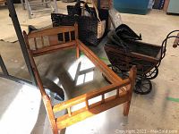 Wooden doll bed with slatted design. Natural wood finish and four legs visible.