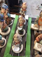 Three Hummel porcelain figurines arranged on a table, seen from front showing detailed facial expressions and painted clothing.