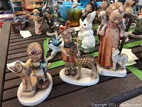 View of the three Hummel figurines grouped together on a wooden surface, showing the hand-painted details and distinct characters.