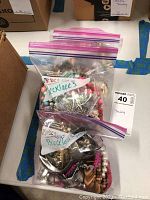 Three bags of assorted costume jewelry on a table, clearly labeled for necklaces and bracelets.