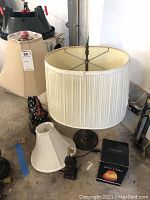 Wide view showing three table lamps and a salt lamp on ground in garage setting.