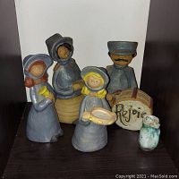 Five Metlox Poppets ceramic figures including four carolers and one man playing a drum with the word 'Rejoice', plus a small pottery vase next to them.