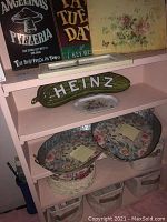 Angelina's Pizzeria and Fat Tuesday signs, yellow floral canvas on shelf along with metal trays and plates underneath.