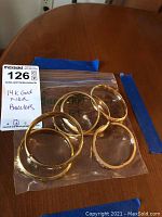 Seven 14K gold filled bracelets displayed in a plastic bag on a wooden table showing the full set from above.