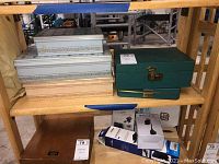 Five jewelry boxes on wooden shelf, three white patterned stacked, one wooden box below, green box to side