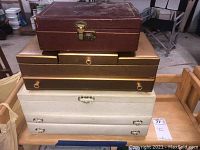 Photo showing all three jewelry boxes stacked on a wooden cart in a garage setting, from a distance.