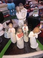Five Willow Tree figurines displayed on a table with other decorative items.