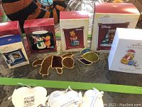 Six Hallmark Winnie the Pooh ornaments in original boxes arranged on a table with one stained glass Pooh design and multiple boxed ornaments.