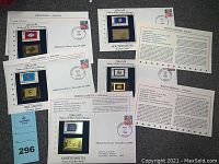 Photo showing 5 22 kt gold State of the Union Stamps for Arkansas, Oklahoma, North Dakota, West Virginia, and South Dakota on display cards with information and postmarks.
