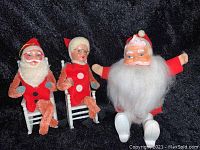 Three antique Christmas decorations from 1954 featuring two small Santa and Mrs. Claus pipe cleaner figurines in white rocking chairs and a larger Santa with pipe cleaner limbs and a fluffy white beard
