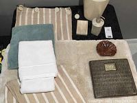Overall bath decor set displayed on black surface, showing shower curtain, towels, bath mats, shell soap dish, soap dispenser, and bath scale