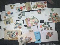Wide view of multiple envelopes and sheets with assorted collectible stamps from various countries sorted by country names handwritten on envelopes.