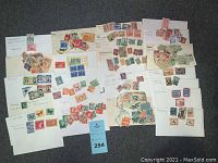 Photo showing multiple envelopes with assorted collectible stamps from various countries spread out for display.