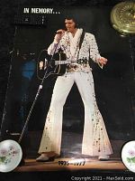 Photo shows Elvis Presley memorial poster in white jumpsuit on black background, with text: In Memory... 1935-1977