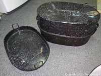 Photo showing the enamelware roasting pan and the roaster with lid stacked next to each other on the floor.