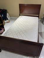 Full view of the assembled twin bed with mattress placed on it demonstrating overall condition and size.