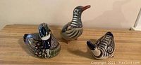 Set of three hand-painted Mexican bird figurines displayed on wooden surface