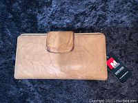 Light brown leather wallet with zip-around edges and snap closure, showing front with embossed Mundi logo and original brand tag.