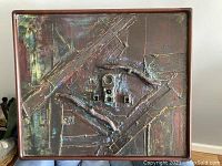 Close up of entire industrial-style sculpture art piece with dark textured background and 3D metal and tube elements, framed, in natural light.