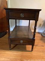 Front view of solid wood end table showing one drawer and turned style legs.