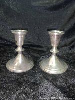 Pair of Towle sterling silver weighted candlestick holders shown side by side on black background, signs of tarnish visible.