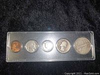 Full view of the coin set in plastic case on black background showing all 5 coins in order from smallest (penny) to largest (half dollar).