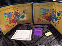 Two open collector's maps showing the US states' quarters arranged with some missing. Certificate of Authenticity and informational booklet placed alongside.