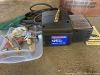 Westward air compressor with 125 PSI label and accessories in plastic bin