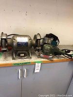 Brico bench grinder, Walter sander, Makita jigsaw on countertop viewed from front