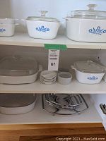 Shelves with multiple Corning Ware baking dishes with lids, small white dishes and ramekins, plus metal serving holders.