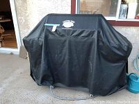 Grill covered by fitted black protective cover with Napoleon logo