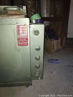 Close-up showing control panel with four knobs and instructional label on the side of the kiln unit, with green metal housing.