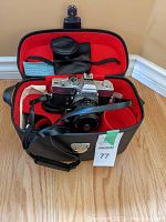 Minolta SR-T 102 camera inside open red-lined black carrying case with lenses, filters and caps.