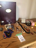 Overview of wooden box and assortment of jewelry on wood surface
