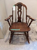 Front view of the solid wood rocking chair showing carved backrest, armrests, and rockers at base.