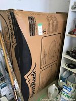 Sealed cardboard box upright in storage area, printed SportRack logo and box outline